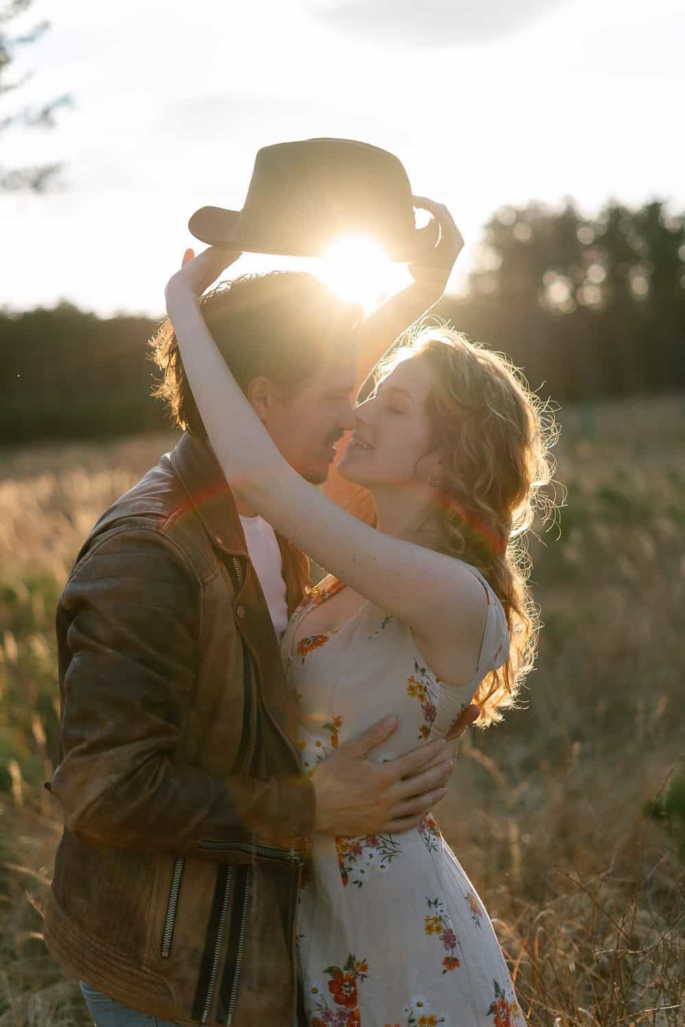 Paar im Sonnenfeld, Frau hebt Hut. Paarfotos in Wien, in der Natur