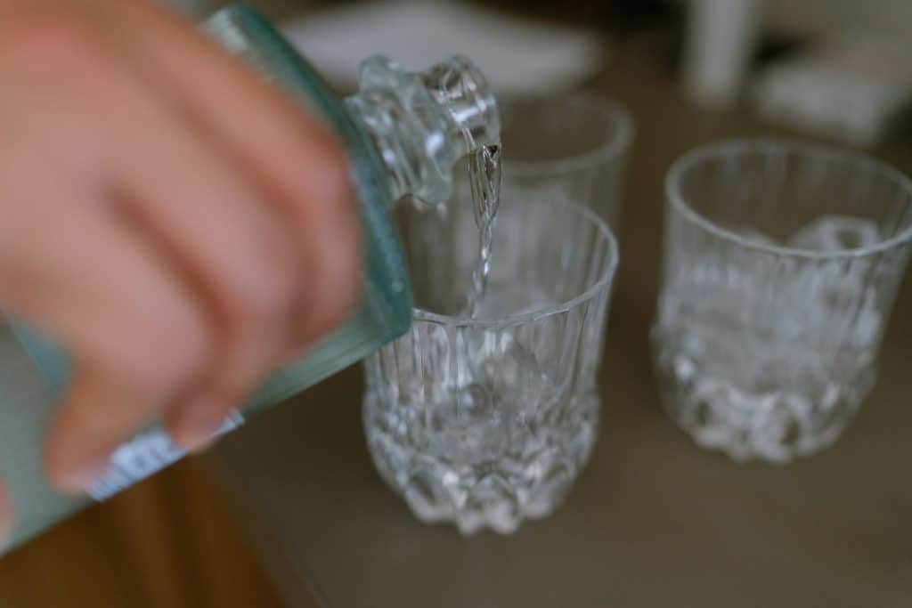 Von Hand gegossenes Getränk in Glas bei Hochzeit unter blauem Himmel.