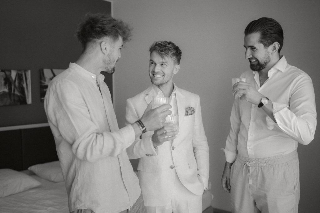 Drei Männer Hochzeit himmelblau Anzug Getränke lächeln drinnen.