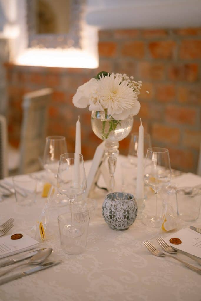 Hochzeit Tischdeko: weiße Blumen, Kerzen, Weingläser, Himmelblau.
