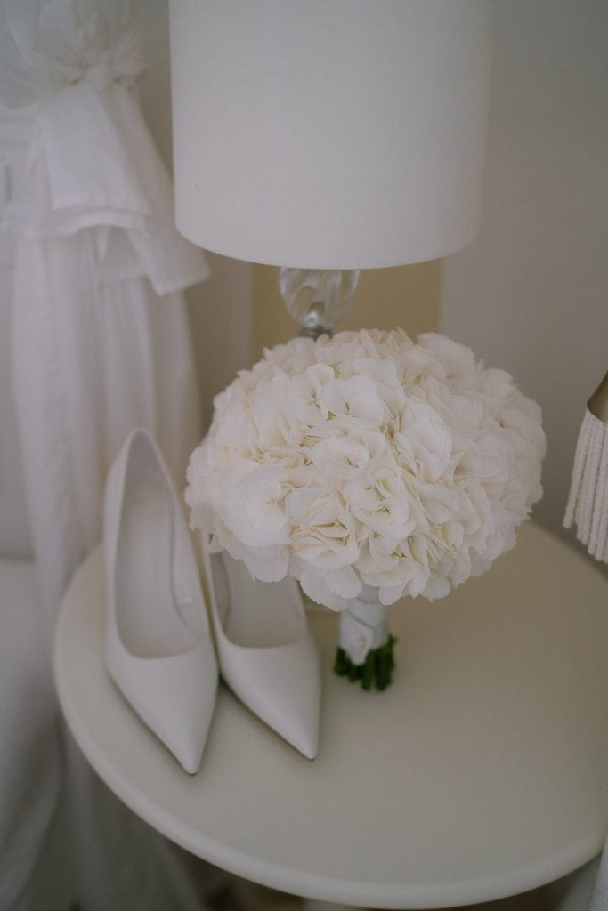 Brautstrauß, Hochzeitsschuhe und Lampe auf weißem Tisch, Himmelblau.