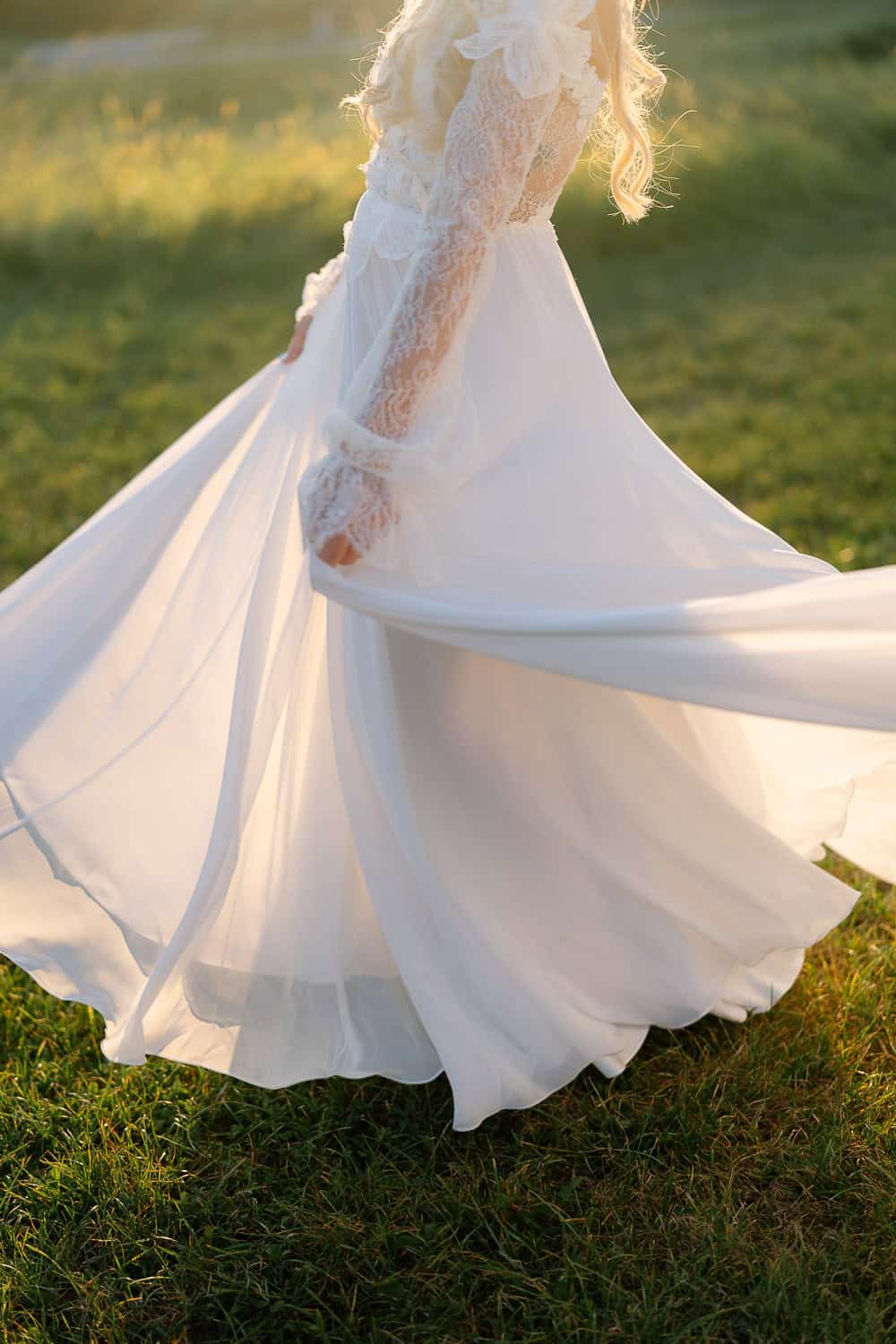 Frau im weißen Kleid tanzt auf sonniger Wiese beim Weingut Holler