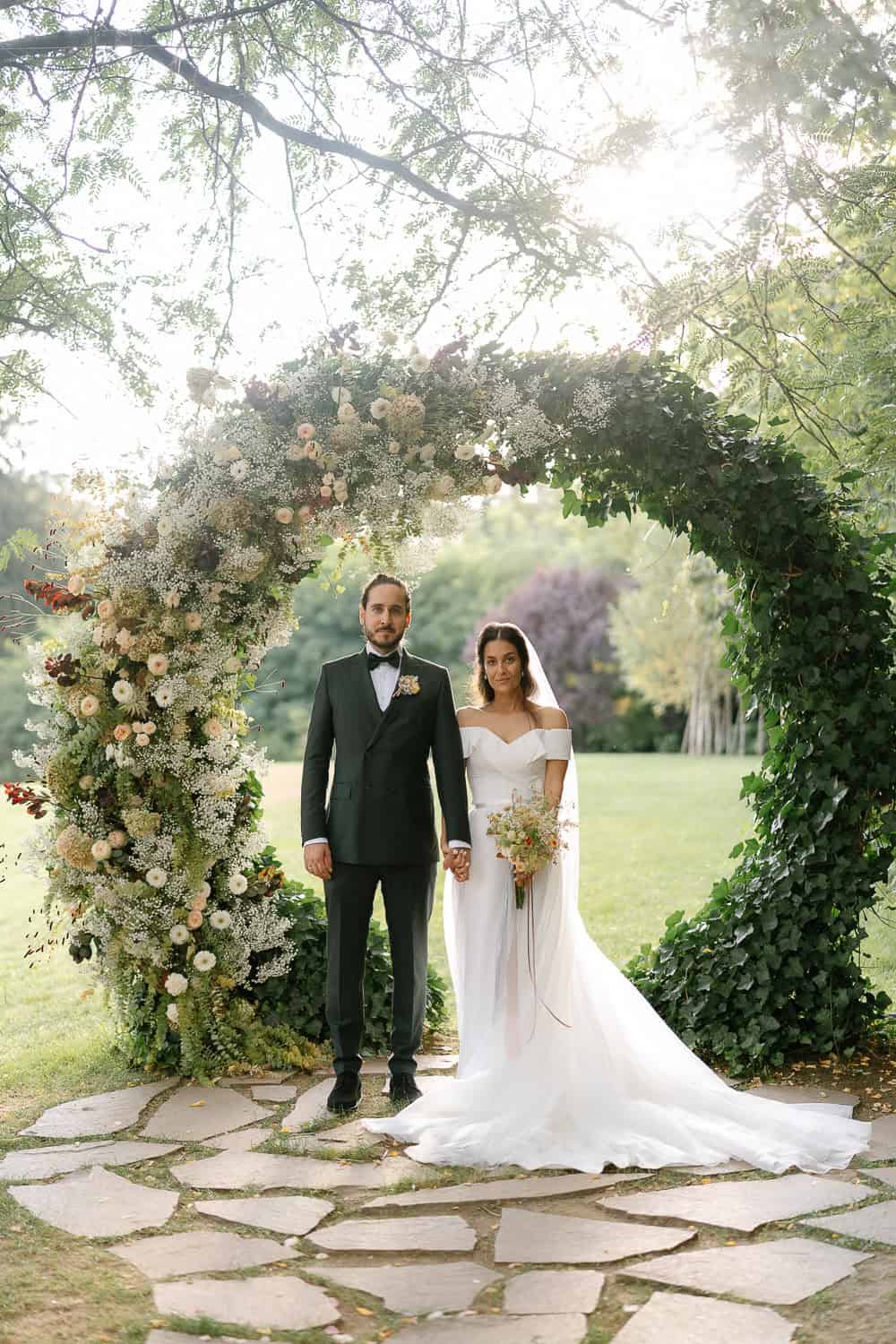 Braut und Bräutigam Hochzeit Bogen Blumen Zeremonie im Freien.