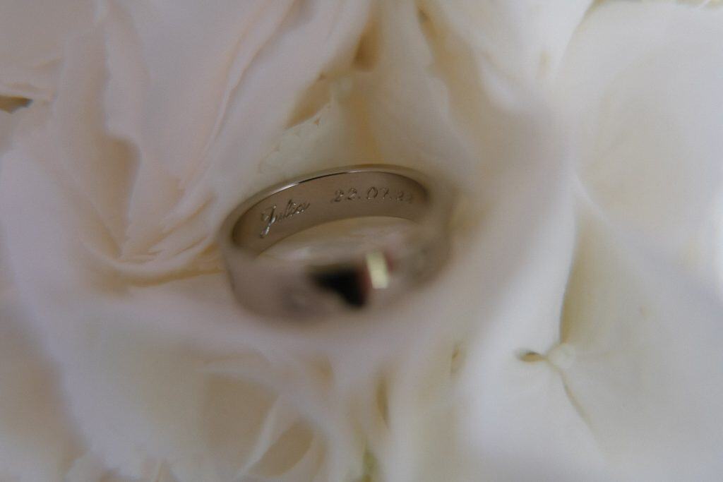 Goldring mit Gravur Julia 22.09.23 auf weißen Blüten.