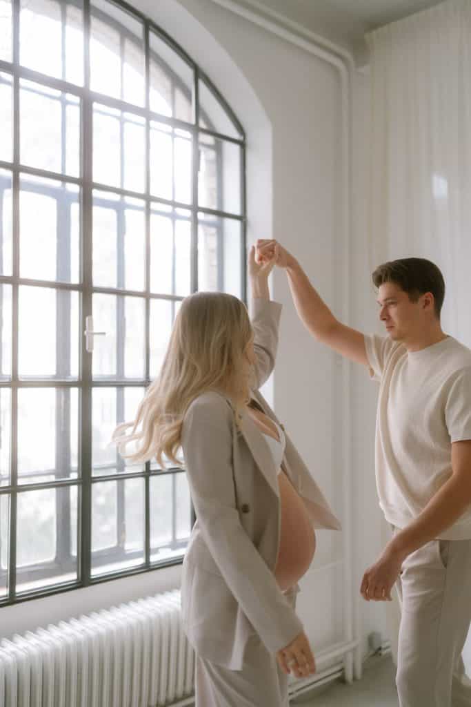 Schwangere tanzt mit Partner beim Babybauch Shooting Wien.