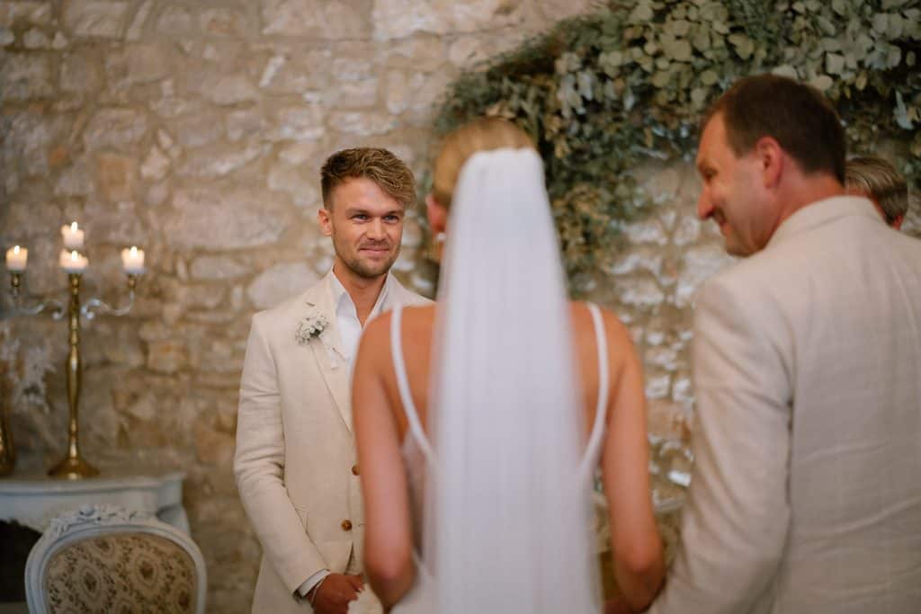 Bräutigam lächelt Braut entgegen, Hochzeit im Himmelblau.