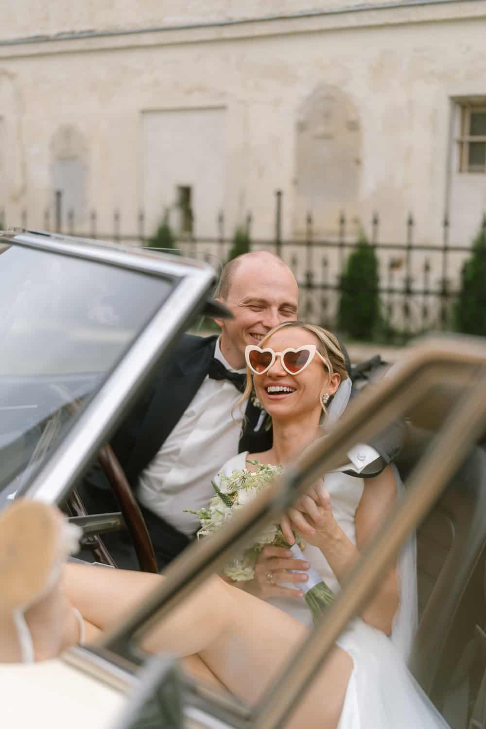 Braut und Bräutigam im Cabrio Hochzeitsauto, Blumenstrauß, lachen.