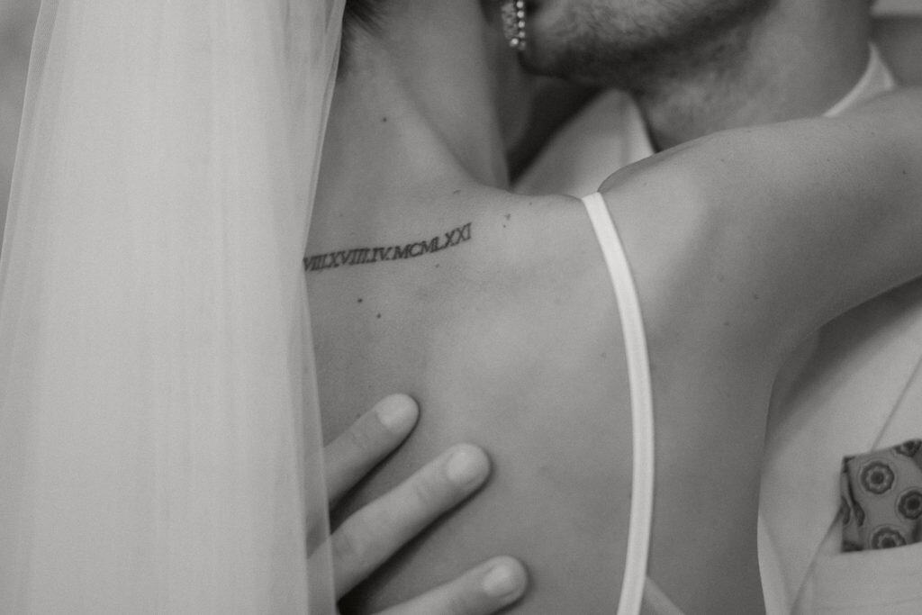 Brautpaar Umarmung Hochzeit im Himmelblau, Tattoo sichtbar.