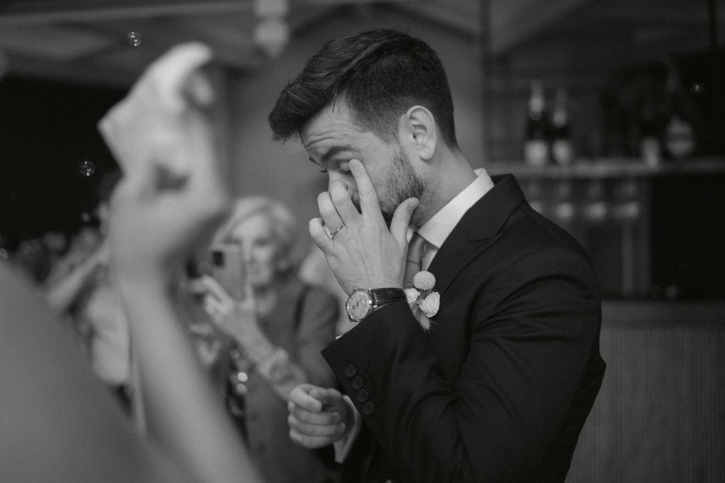 Bräutigam weint bei Hochzeit im Fernblick, schwarz-weiß.