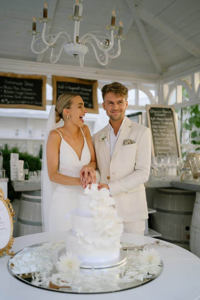 Brautpaar schneidet Hochzeitstorte bei Hochzeit im Himmelblau.