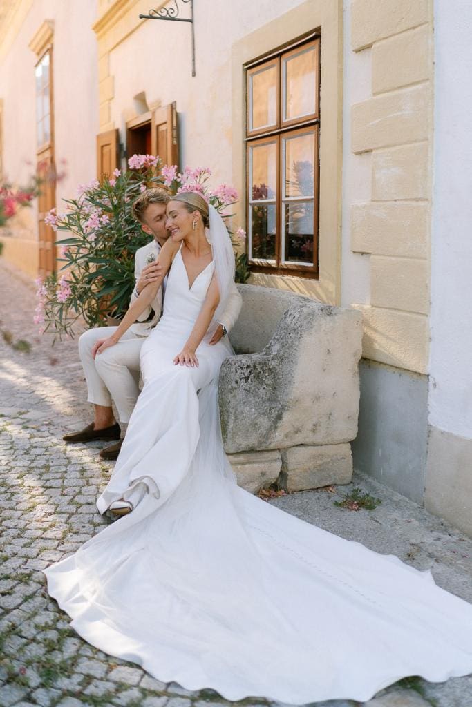 Braut und Bräutigam auf Steinbank in Rust. Hochzeit im Himmelblau