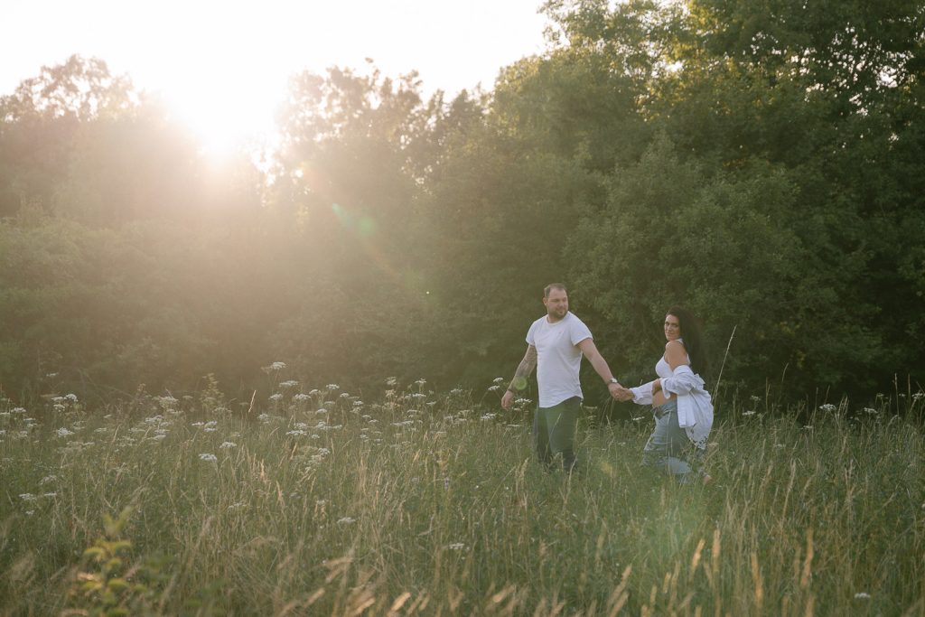Paar im Sonnenuntergang, Hand in Hand, Wiese, Wildblumen, romantisches Fotoshooting.