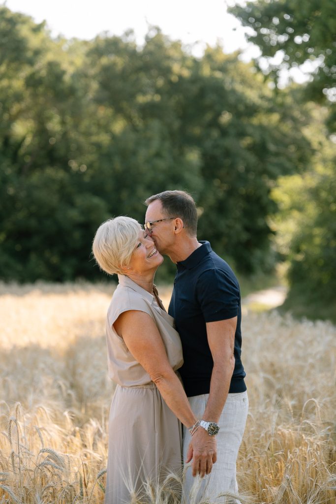 Älteres Paar glücklich im Sonnenfeld, Mann küsst Frau Stirn.