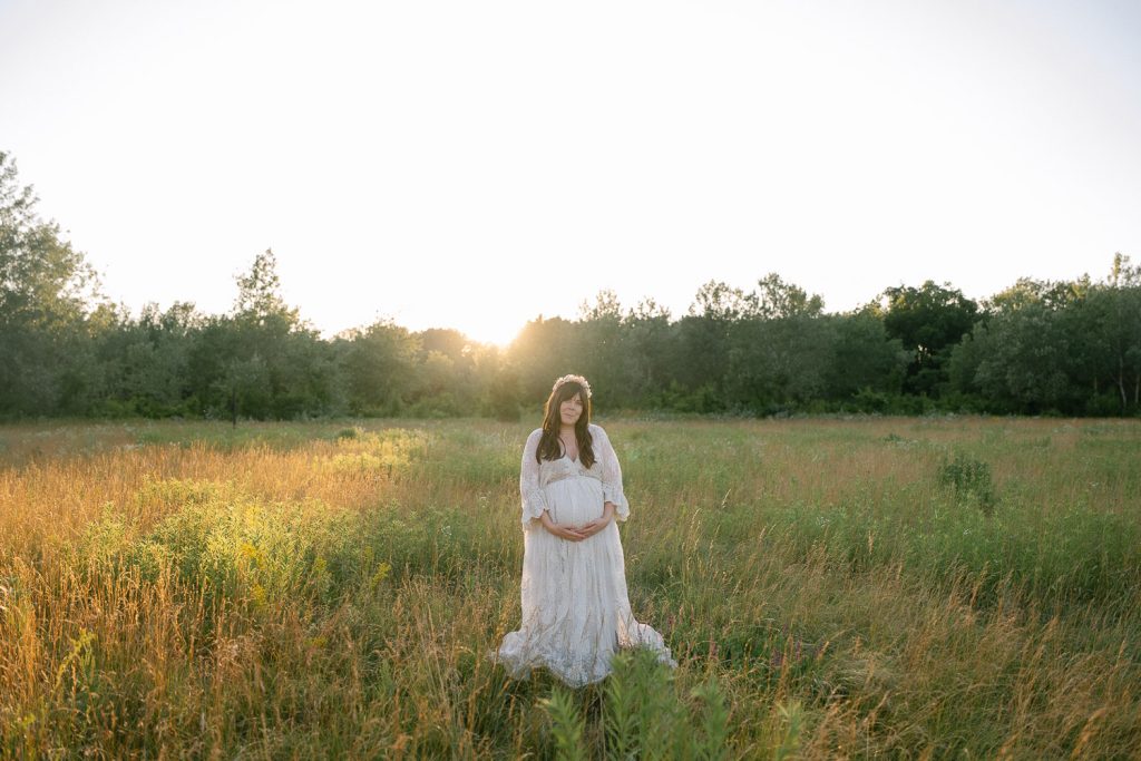 Schwangere Frau im weißen Kleid im sonnigen Feld Fotoshooting.