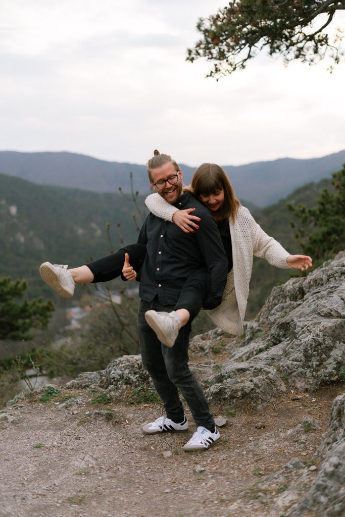 Paar Fotoshooting: Mann trägt Frau, Berge, Natur, Felsenweg.