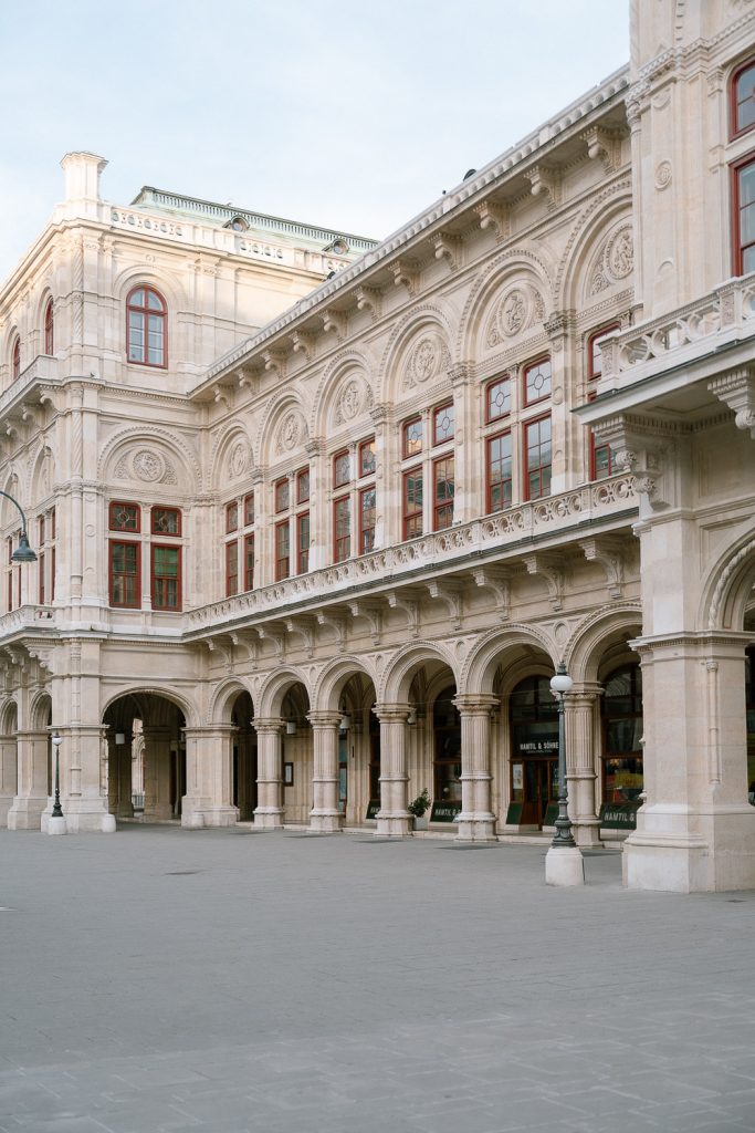 Historisches Gebäude mit roten Fensterrahmen, Steinornamenten, Arkaden, Filmlocation.