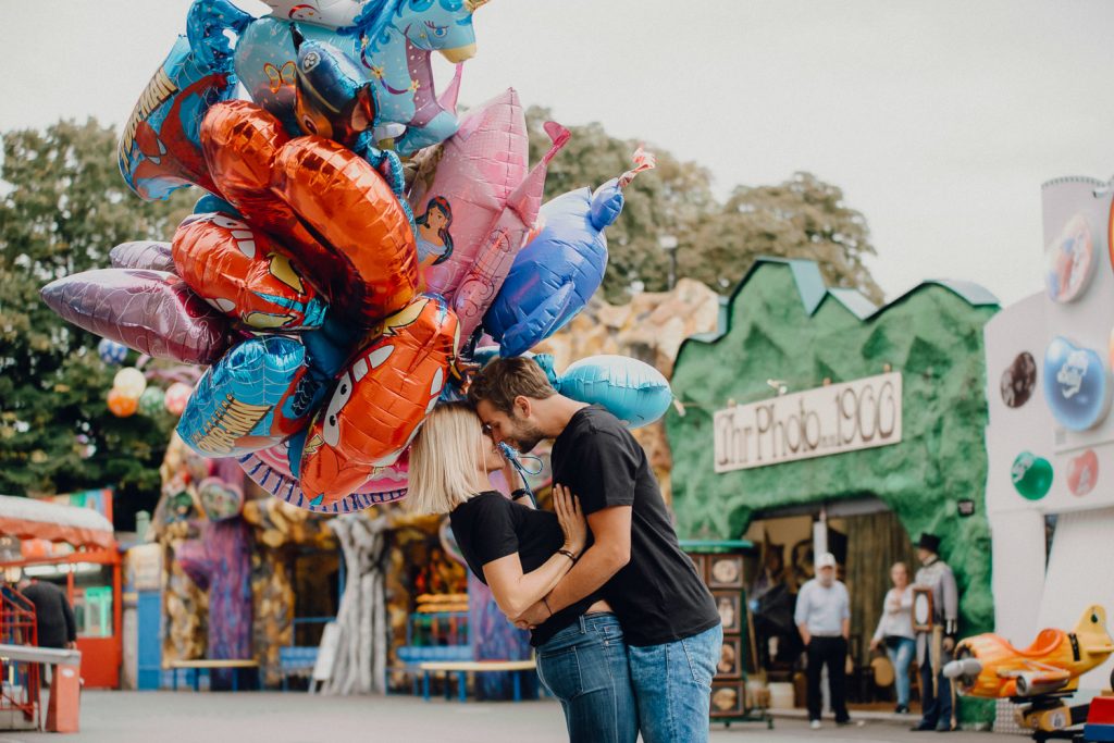 Paar umarmt sich mit bunten Ballons im Freizeitpark.