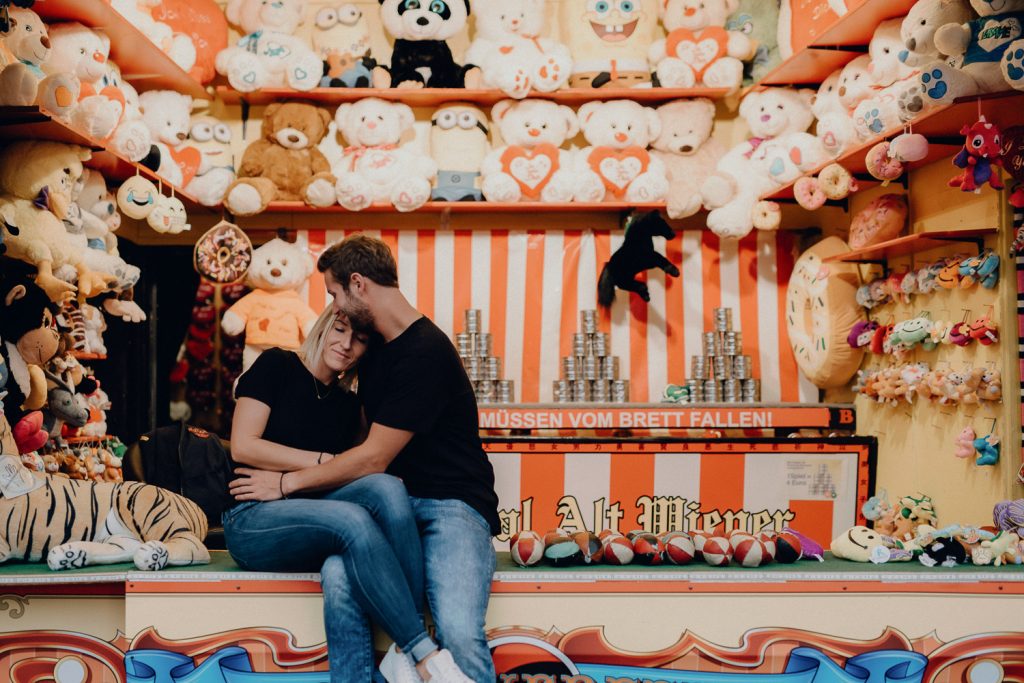 Pärchen am Stand für Karnevalsspiele, Plüschtiere, schwarze Hemden, Jeans.