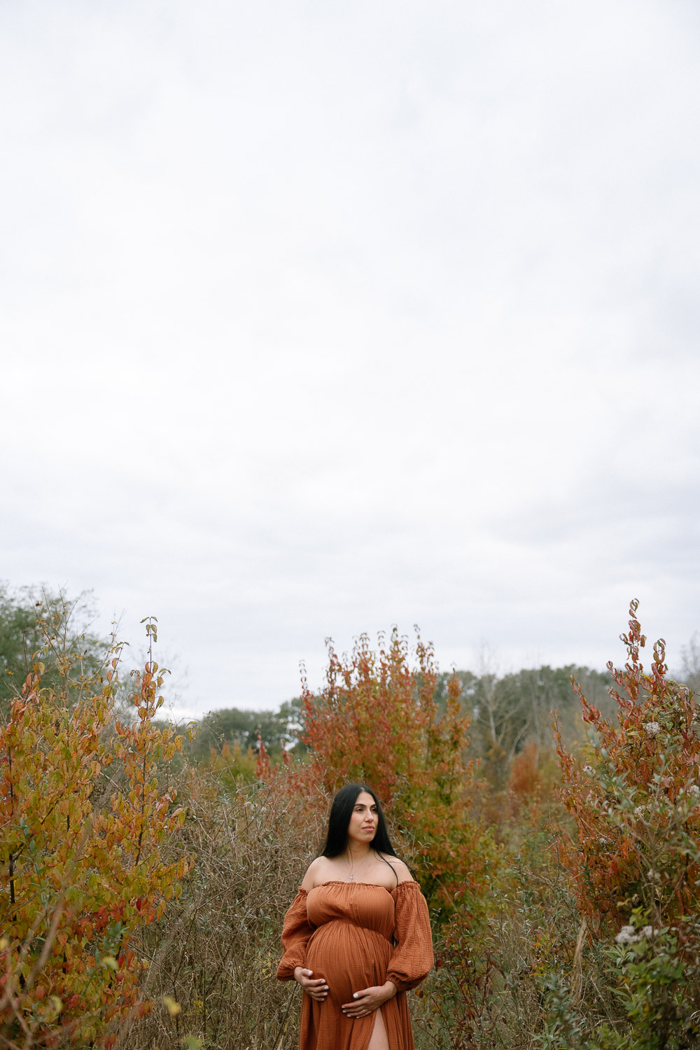 Schwangere Frau bei herbstlichem Babybauchshooting in Wien, umgeben von buntem Laub