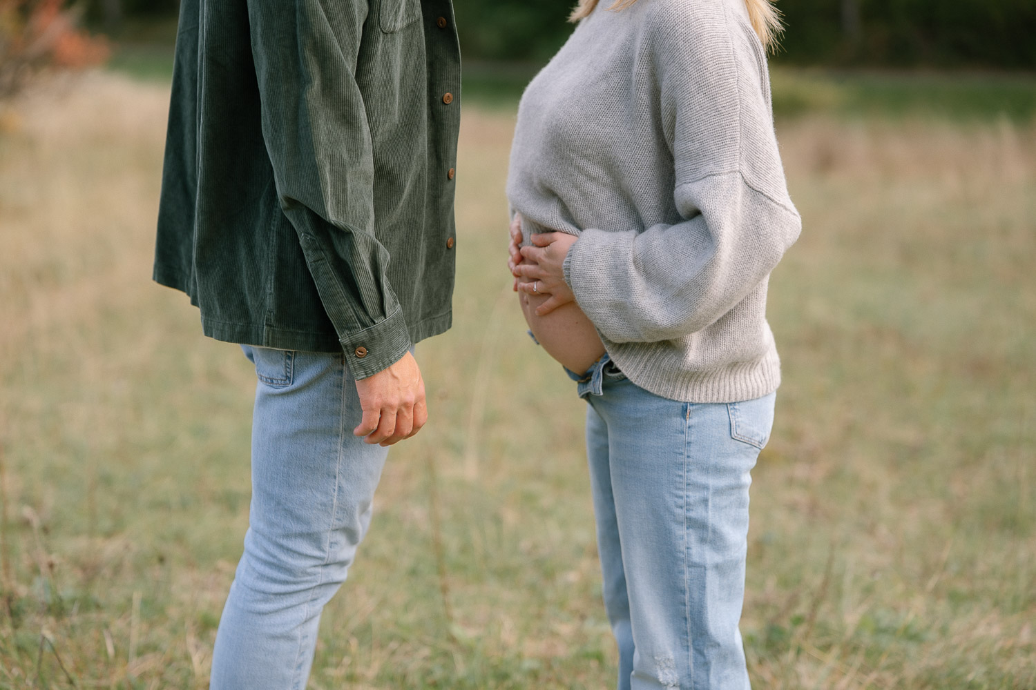 Babybauchfoto mit Fokus auf Bauch und Hände eines Paares in Wien