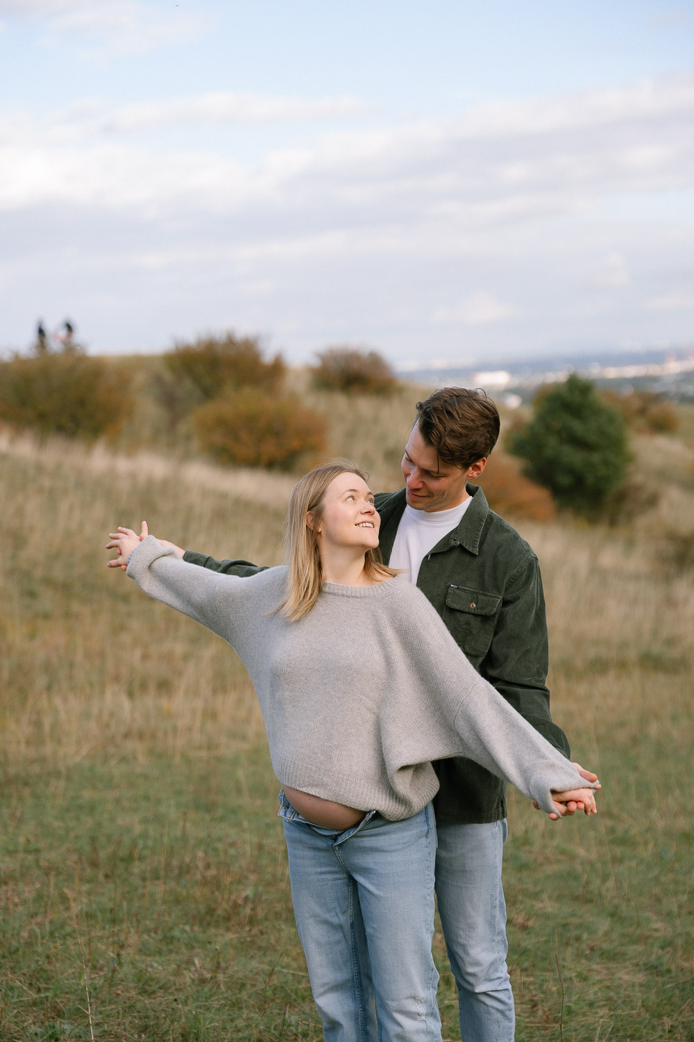 Fröhliches Paar beim Babybauchshooting in der Natur von Wien