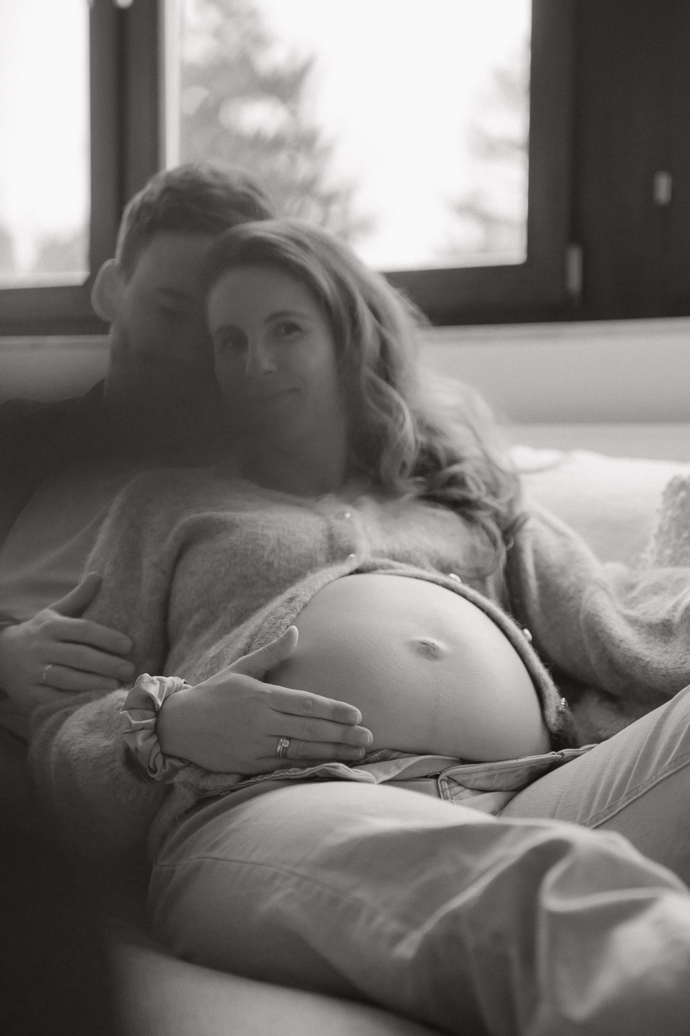 Schwangerschaftsfotografie auf der Couch in Wien, inniger Moment mit Babybauch in Schwarz-Weiß