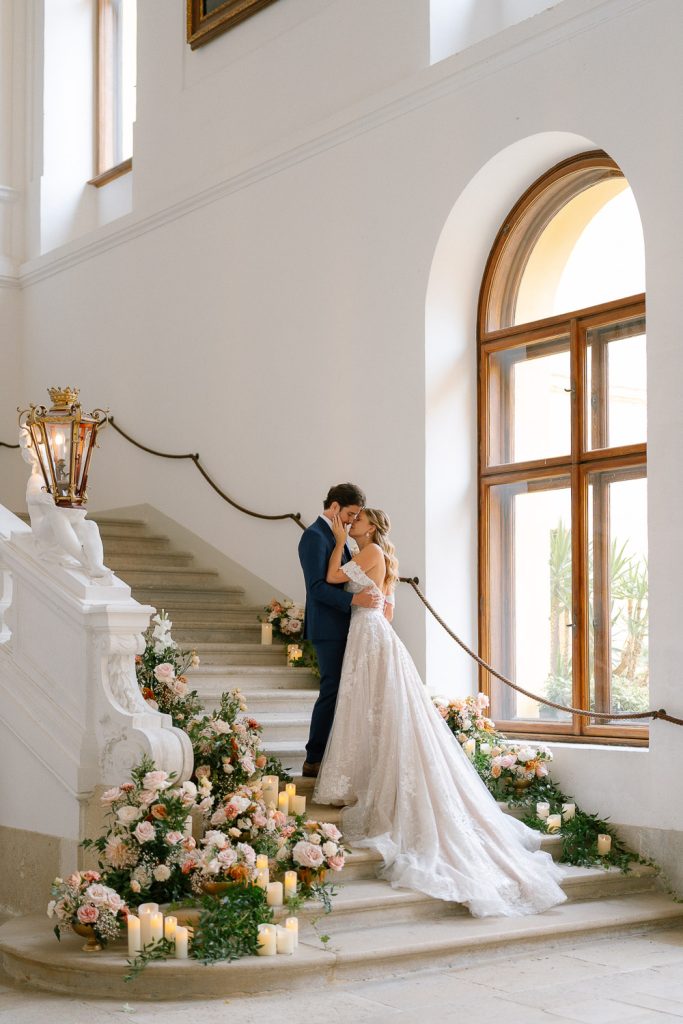 Brautpaar küsst sich bei der romantischen Trauung auf der Treppe des Schlosses Eckartsau