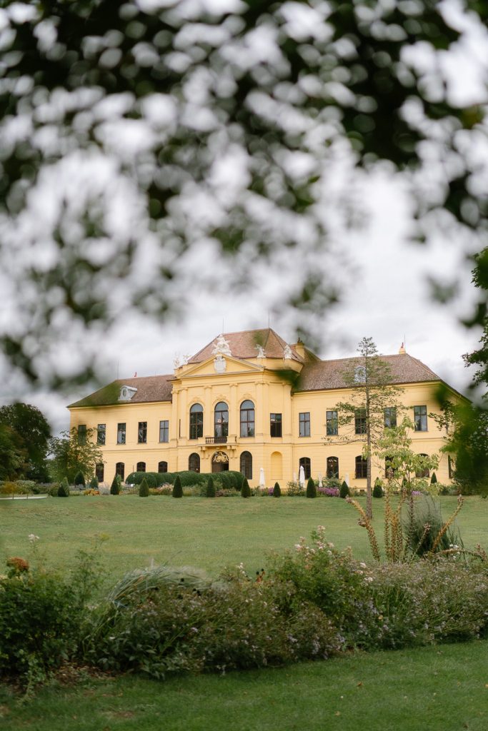 Außenansicht des gelben Schlosses Eckartsau mit gepflegter Gartenanlage im Spätsommer